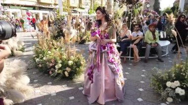 TIMISOARA, ROMANIA - 19 Nisan 2019: Zafer Meydanı, TIMFLORALIS Uluslararası Çiçek Festivali. Festivalin kraliçesi çiçekli bir elbise giyerek sokakta yürüyor..