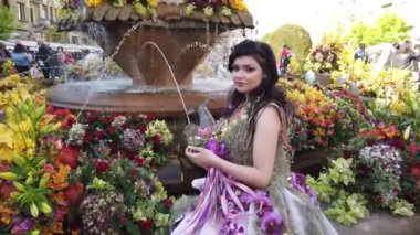 TIMISOARA, ROMANIA - 19 Nisan 2019: Zafer Meydanı, TIMFLORALIS Uluslararası Çiçek Festivali. Festivalin kraliçesi çiçekli bir elbise giyerek sokakta yürüyor..
