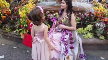 TIMISOARA, ROMANIA - 19 Nisan 2019: Zafer Meydanı, TIMFLORALIS Uluslararası Çiçek Festivali. Festivalin kraliçesi çiçekli bir elbise giyerek sokakta yürüyor..