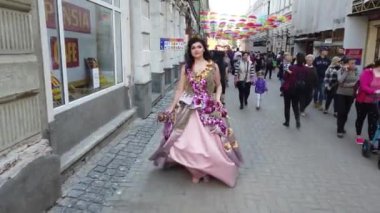 TIMISOARA, ROMANIA - 19 Nisan 2019: Zafer Meydanı, TIMFLORALIS Uluslararası Çiçek Festivali. Festivalin kraliçesi çiçekli bir elbise giyerek sokakta yürüyor..