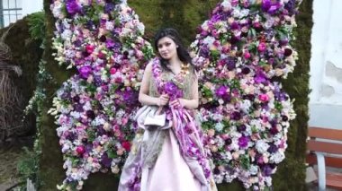 TIMISOARA, ROMANIA - 19 Nisan 2019: Zafer Meydanı, TIMFLORALIS Uluslararası Çiçek Festivali. Festivalin kraliçesi çiçekli bir elbise giyerek sokakta yürüyor..