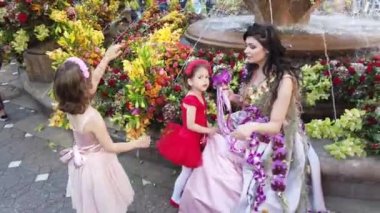 TIMISOARA, ROMANIA - 19 Nisan 2019: Zafer Meydanı, TIMFLORALIS Uluslararası Çiçek Festivali. Festivalin kraliçesi çiçekli bir elbise giyerek sokakta yürüyor..