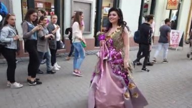 TIMISOARA, ROMANIA - 19 Nisan 2019: Zafer Meydanı, TIMFLORALIS Uluslararası Çiçek Festivali. Festivalin kraliçesi çiçekli bir elbise giyerek sokakta yürüyor..