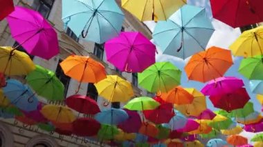 Çok renkli şemsiyeler güneşli bir günde sokakta asılı.