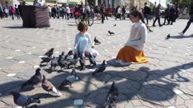 TIMISOARA, ROMANIA - 19 Nisan 2019: çocuklar şehir merkezinde güvercinlerle oynuyorlar