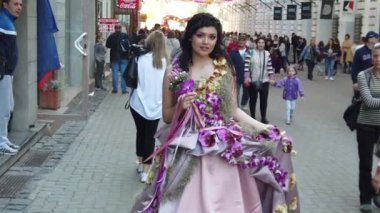 TIMISOARA, ROMANIA - 19 Nisan 2019: Zafer Meydanı, TIMFLORALIS Uluslararası Çiçek Festivali. Çiçekli bir elbise giyen festivalin kraliçesi sokakta yürüyor. Yavaş çekim görüntüleri