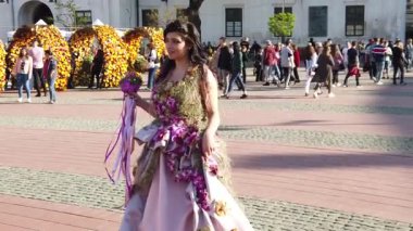 TIMISOARA, ROMANIA - 19 Nisan 2019: Zafer Meydanı, TIMFLORALIS Uluslararası Çiçek Festivali. Çiçekli bir elbise giyen festivalin kraliçesi sokakta yürüyor. Yavaş çekim görüntüleri