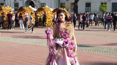 TIMISOARA, ROMANIA - 19 Nisan 2019: Zafer Meydanı, TIMFLORALIS Uluslararası Çiçek Festivali. Çiçekli bir elbise giyen festivalin kraliçesi sokakta yürüyor. Yavaş çekim görüntüleri
