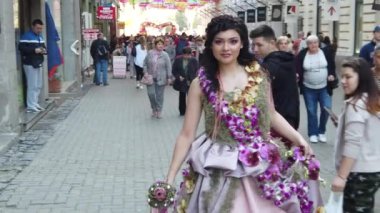 TIMISOARA, ROMANIA - 19 Nisan 2019: Zafer Meydanı, TIMFLORALIS Uluslararası Çiçek Festivali. Çiçekli bir elbise giyen festivalin kraliçesi sokakta yürüyor. Yavaş çekim görüntüleri