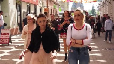 TIMISOARA, ROMANIA - 19 Nisan 2019: Zafer Meydanı, TIMFLORALIS Uluslararası Çiçek Festivali. Farklı etnik kökenden insanlar renkli şemsiyeler altında yürüyorlar. Yavaş çekim görüntüleri