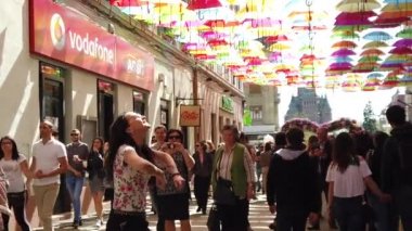 TIMISOARA, ROMANIA - 19 Nisan 2019: Zafer Meydanı, TIMFLORALIS Uluslararası Çiçek Festivali. Farklı etnik kökenden insanlar renkli şemsiyeler altında yürüyorlar. Yavaş çekim görüntüleri