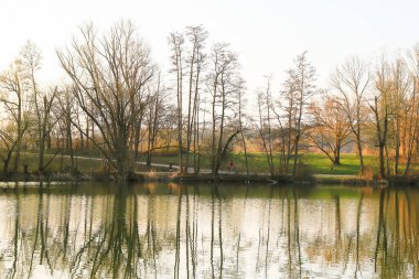 Regensburg, Almanya - 25 Mart 2022: İnsanlar gün batımında Tuna Nehri boyunca, Almanya, Regensburg, Avrupa 'da kırsal bir yolda bisiklete biniyorlar..