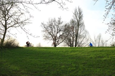 Regensburg, Almanya - 12 Nisan 2022: İnsanlar gün batımında Tuna Nehri boyunca, Almanya, Regensburg, Avrupa 'da kırsal bir yolda bisiklete biniyorlar..