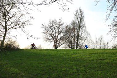 Regensburg, Almanya - 12 Nisan 2022: İnsanlar gün batımında Tuna Nehri boyunca, Almanya, Regensburg, Avrupa 'da kırsal bir yolda bisiklete biniyorlar..