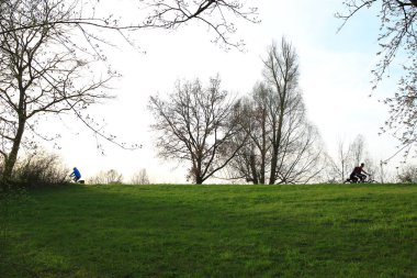 Regensburg, Almanya - 12 Nisan 2022: İnsanlar gün batımında Tuna Nehri boyunca, Almanya, Regensburg, Avrupa 'da kırsal bir yolda bisiklete biniyorlar..