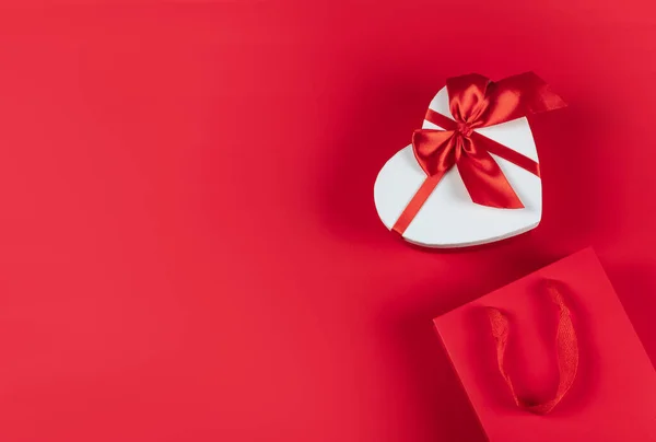 Piatto. Imballaggio per acquisti, regali e pacchi su sfondo rosso. Il concetto di consegna di regali e pacchi per le vacanze San Valentino, piacevoli sorprese. Shopping, vendita, promozione. — Foto Stock