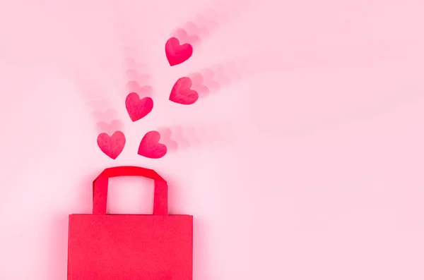 Online nákupní koncept. Horní pohled na dárkové tašky a růžové papírové srdíčka na růžovém pozadí s zvlněným efektem, kopírovací prostor, plochý ležel. Pozadí pro Valentýna, Narozeniny, Den matek — Stock fotografie
