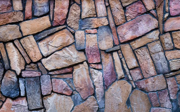 Стена выполнена из разноцветного натурального камня, кладка каменная на цементе. Концепция - каменные обои, фон и декор — стоковое фото