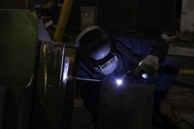 Becerikli kaynakçılar fabrikada paslanmaz çelik kaynak yapar. İnşaat alanı metal kaynakçısı. İnşaatçılar iş yerinde güvenlik için yangın geçirmez eldiven giyerler. yüksek çalışma