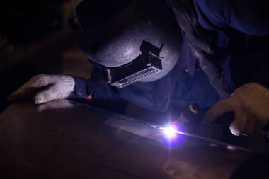 Becerikli kaynakçılar fabrikada paslanmaz çelik kaynak yapar. İnşaat alanı metal kaynakçısı. İnşaatçılar iş yerinde güvenlik için yangın geçirmez eldiven giyerler. yüksek çalışma