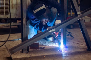 Becerikli kaynakçılar fabrikada paslanmaz çelik kaynak yapar. İnşaat alanı metal kaynakçısı. İnşaatçılar iş yerinde güvenlik için yangın geçirmez eldiven giyerler. yüksek çalışma