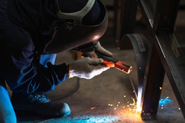 Becerikli kaynakçılar fabrikada paslanmaz çelik kaynak yapar. İnşaat alanı metal kaynakçısı. İnşaatçılar iş yerinde güvenlik için yangın geçirmez eldiven giyerler. yüksek çalışma