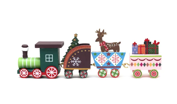 Eine Spielzeuglokomotive trägt in den Waggons einen Weihnachtsbaum, einen Hirsch und Geschenke. Fest der Geburt Christi. Isoliertes Foto für Design. — Stockfoto