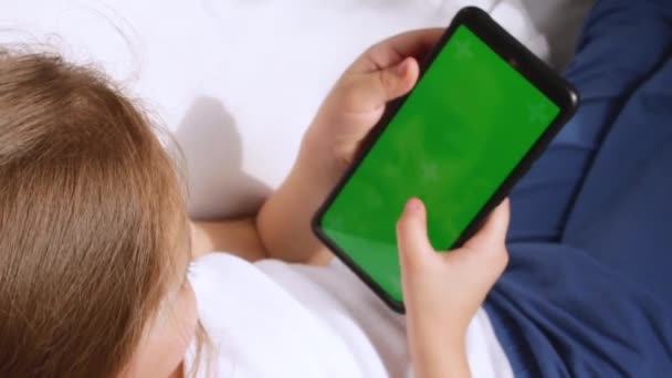 Un niño con un teléfono en las manos. Pantalla verde. Teléfono juego. — Vídeos de Stock