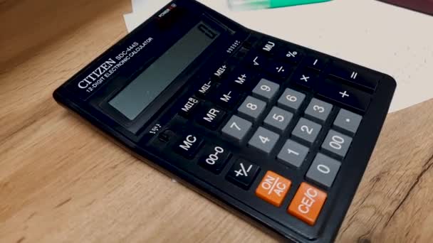 Черный калькулятор лежит на рабочем столе. Отчет или подсчет, рабочие моменты. — стоковое видео