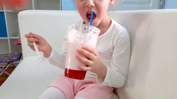 A little girl smiles and drinks an oxygen cocktail. Vitamin drink. Health treatments. Slow motion video — Wideo stockowe