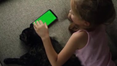 Kedili bir çocuk telefona bakar. Cep telefonu çocukların elindedir. Krom yeşil ekran. Omzunun üstünden bak. Çocukların internet içeriğine bak. Video.