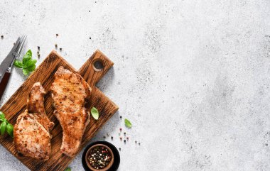 Metnin altındaki tahtanın üzerinde baharatlı iki kızarmış domuz bifteği.