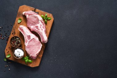 Arkaplanda baharat ve fesleğenli çiğ domuz bifteği. Üst Manzara. Taze et. Kaburgalar.