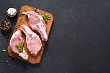 Arkaplanda baharat ve fesleğenli çiğ domuz bifteği. Üst Manzara. Taze et. Kaburgalar.