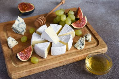 Camembert peyniri ve üzümlü mavi peynir tabağı, incir, tahta tahtada bal. Peynir tabağı