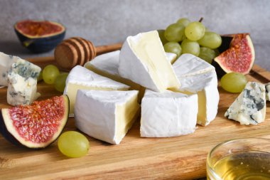 Camembert peyniri ve üzümlü mavi peynir tabağı, incir, tahta tahtada bal. Peynir tabağı