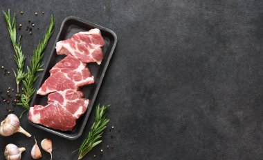 Siyah arka planda sarımsaklı ve biberiyeli bir tepside sığır eti. Taze et..