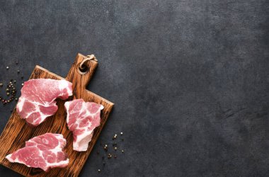 Siyah arka planda, en üst görüntüde, panoda sığır eti var. Taze et..