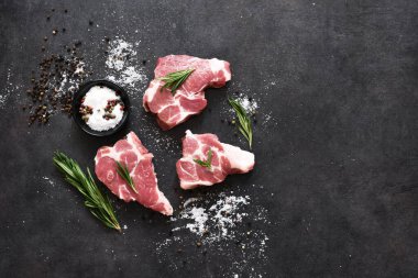 Taze et, siyah taştan bir arka planda sığır eti, tuz ve biberiye, üst görünüm..