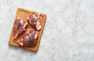 Ahşap bir tahtada biftek, beton bir arka planda baharatlar, üst manzara..