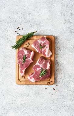 Ahşap bir tahtada biftek, beton bir arka planda baharatlar, üst manzara..