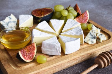 Camembert peyniri ve üzümlü mavi peynir tabağı, incir, tahta tahtada bal. Peynir tabağı
