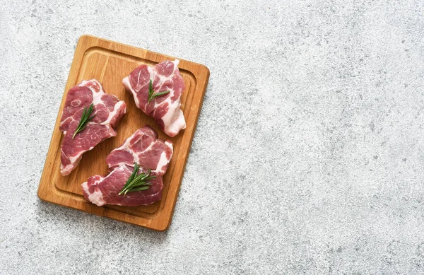 Ahşap bir tahtada biftek, beton bir arka planda baharatlar, üst manzara..