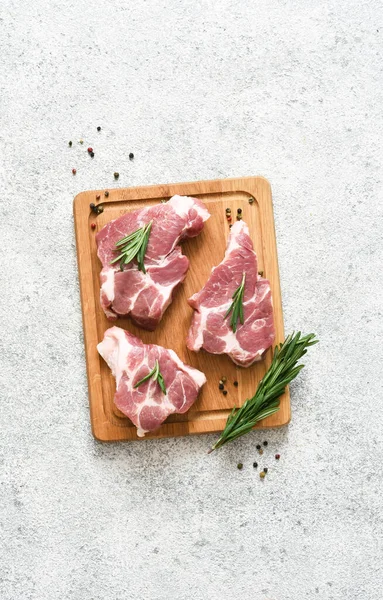 Ahşap bir tahtada biftek, beton bir arka planda baharatlar, üst manzara..