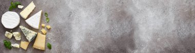 Beton zemin üzerinde çeşitli peynir türleri, üst görünüm.