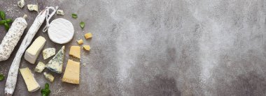 Beton zeminde çeşitli peynirler ve küflü sosisler. Yukarıdan bak. Reklamcılık. Yemek teslimatı.