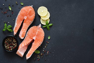 Siyah arka planda baharat ve klematisi olan çiğ kırmızı balık. Üst Manzara. Somon bifteği.