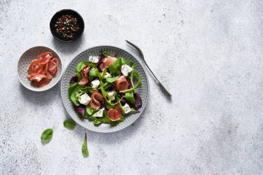 Arugula salatası, mavi peynirli pazı ve beton arka planda soslu jambon..