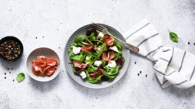 Arugula salatası, mavi peynirli pazı ve beton arka planda soslu jambon..