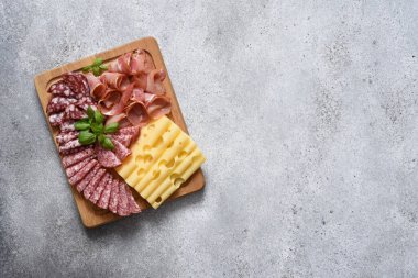 Lezzetli. Peynir, prosciutto, beton arka planda ahşap bir tahta üzerinde salam..